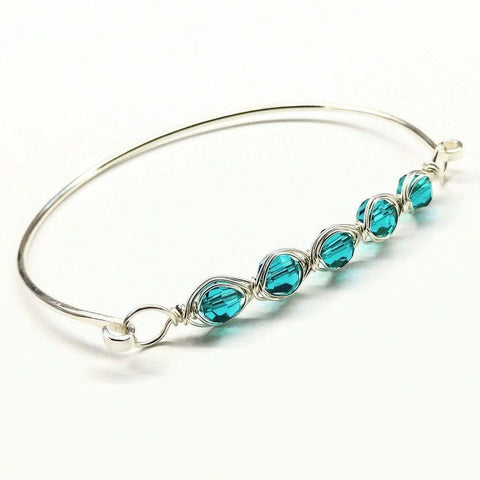 The Larger Oval Shaped Swarovski Crystal Bar Bangle Bracelet by Alexa Martha Designs features five turquoise blue Swarovski crystals wrapped with silver wire in a row, designed to fit an 8-inch wrist.