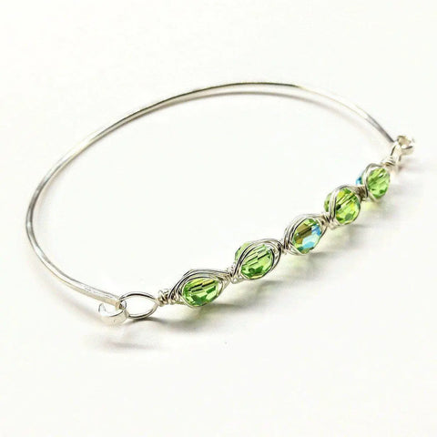 The Alexa Martha Designs Larger Oval Shaped Swarovski Crystal Bar Bangle Bracelet features five green crystals wire wrapped in a row on sterling silver to fit an 8-inch wrist, shown on a white background.