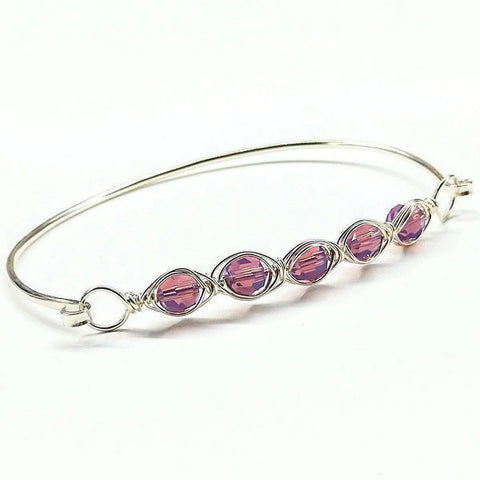The Alexa Martha Designs Larger Oval Shaped Swarovski Crystal Bar Bangle Bracelet fits an 8-inch wrist and features five purple Swarovski crystals wrapped in decorative wire, elegantly displayed in a row at the center on a white background.