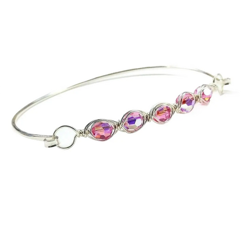The Larger Oval Shaped Swarovski Crystal Bar Bangle Bracelet by Alexa Martha Designs features sparkling crystals on a sterling silver bangle, wire-wrapped for elegance, and displayed against a white background.
