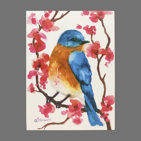 JuLu Cards’ Pack of 4 - Brown and Blue Bird With Pink Flowers (20020) features a watercolor bird with blue and orange feathers on pink blossoms, ideal for greeting cards. Each card includes the artist’s signature in the lower left corner.