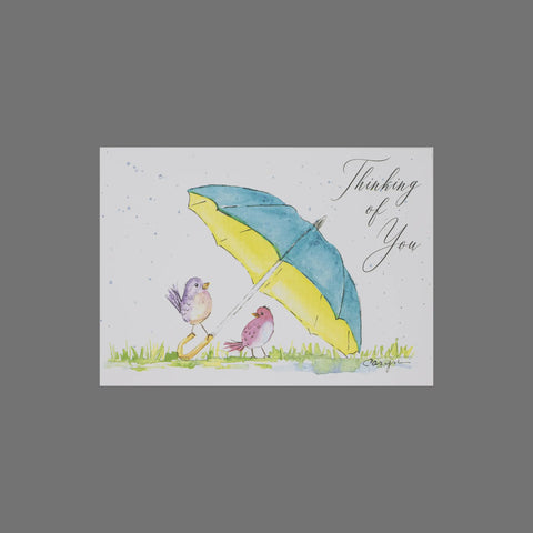 JuLu Cards’ Pack of 8 Thinking of You With Umbrella and Birds (10087) features two birds under a yellow and blue umbrella on grass. Each 3.5x5 card with envelopes has a white background with light blue splatters.
