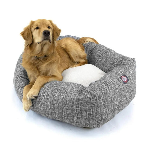 A golden retriever relaxes in the Majestic Pet Palette Heathered Sherpa Bagel Dog Bed, a gray cushioned bed with spine support and a white inner pad. Its machine washable design ensures easy cleaning and lasting comfort.