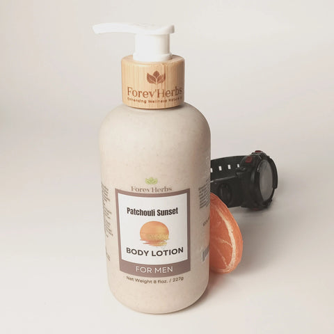 A bottle of Forev'Herbs Patchouli Sunset Lotion stands on a white surface beside a black wristwatch and an orange grapefruit slice.