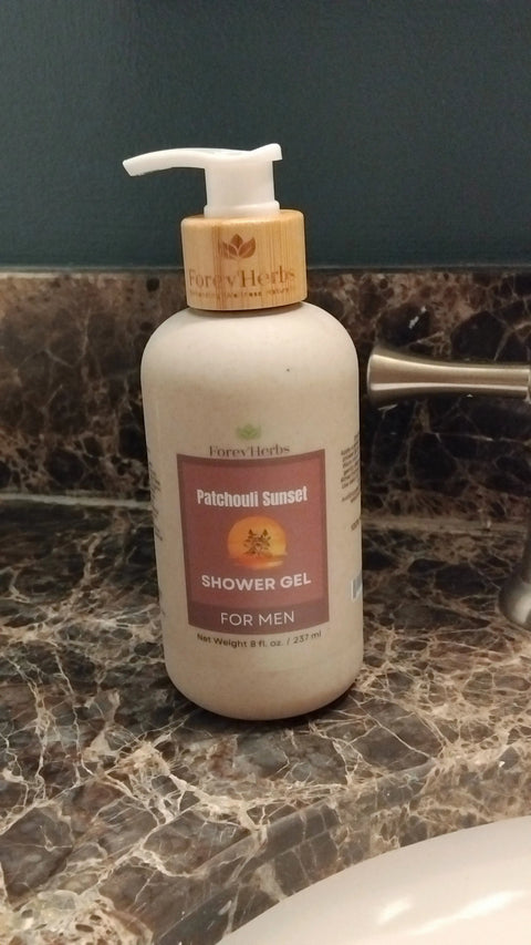 A bottle of Forev'Herbs Patchouli Sunset Shower Gel rests on a brown marble bathroom counter beside a metal faucet.