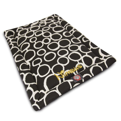 The Fusion Crate Mat - Personalized by Majestic Pet is a rectangular black pet bed with a white circular pattern, yellow embroidered Nimbus, and a red and white corner tag. Made with premium polyester batting, it’s machine washable and perfect for crates.