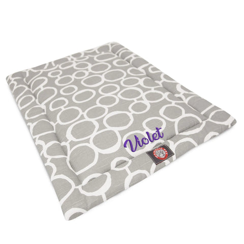 The Majestic Pet Fusion Crate Mat - Personalized is a gray bed with white circles, featuring Violet embroidered in purple on one side. Made with premium polyester batting, it has a small red and white tag on the front edge.