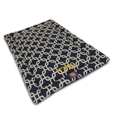 The Majestic Pet Links Crate Mat - Personalized features navy blue polyester with a white chain-link pattern, the name Theo embroidered in yellow, and a red and silver emblem. Use as a washable pet mattress or dog crate mat.