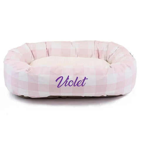The Majestic Pet Anderson Check Sherpa Bagel Bed - Personalized features pink and white plaid, a cozy cream interior, cushioned sides for spine support, and Violet in purple script on the front.