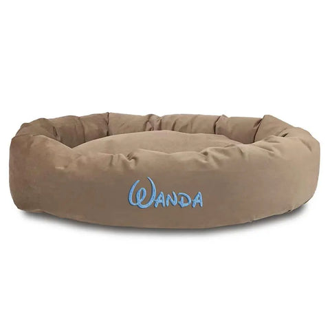 The Majestic Pet Suede Bagel Dog Bed - Personalized is a round, plush brown suede bed with raised sides and Wanda embroidered in light blue. It features a removable slipcover for easy cleaning.