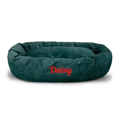 The Majestic Pet Villa Bagel Dog Bed - Personalized features a dark green oval shape, plush fabric, raised edges, and Daisy embroidered in red on the front.