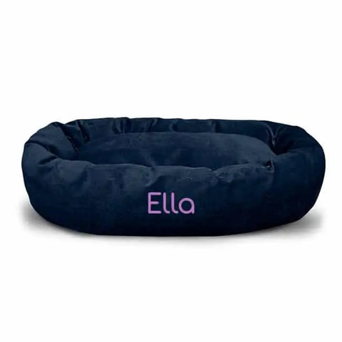 The Majestic Pet Villa Bagel Dog Bed - Personalized, in dark blue oval micro-velvet, features Ella embroidered in light pink on the front. Soft and plush, it offers comfort and style for your pet.