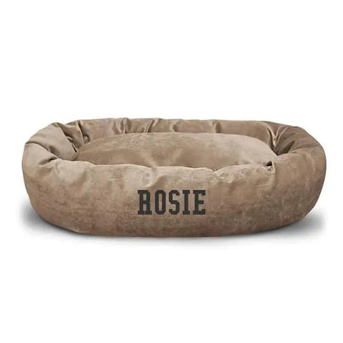 The Majestic Pet Villa Bagel Dog Bed - Personalized features soft polyester micro-velvet in tan, a round plush design, and ROSIE printed in bold black letters on the front.