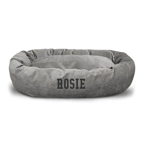 The Majestic Pet Villa Bagel Dog Bed - Personalized is a round, gray plush bed with raised sides. The name ROSIE is printed in bold black letters on the front, creating a cozy and customized spot for your pet.