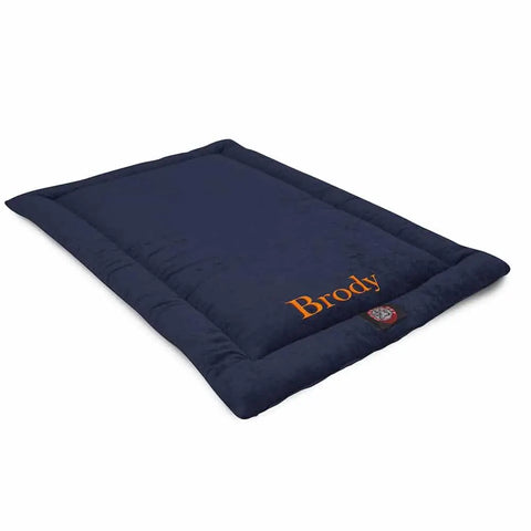 A rectangular, navy blue Majestic Pet Villa Crate Mat—Personalized with Brody embroidered in orange—rests on a white background. This machine-washable dog mat delivers comfort and easy care.