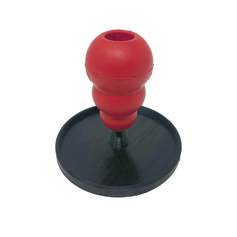 A red, bulb-shaped Kong-compatible freezer dog toy sits vertically on the black Chatelet Manufacturing Pet Toy Freezer Holder Stand, photographed against a white background.