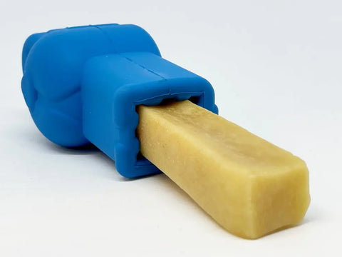 The SodaPup Petz Yak Chew Holder EDispenser secures a rectangular beige yak chew, which extends outward from the blue rubber holder against a white background.