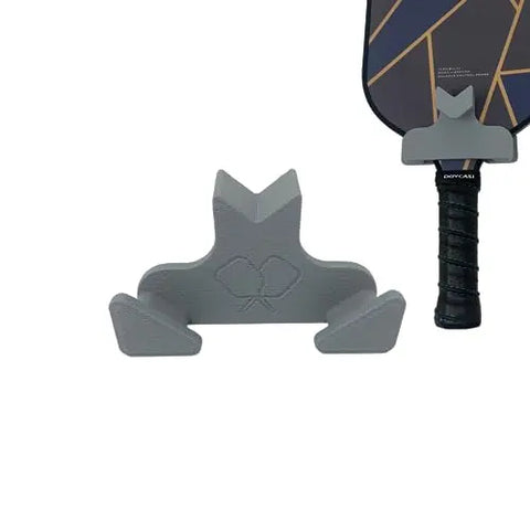 The Chatelet Manufacturing Pickleball Paddle Chain Link Fence Holder is a gray, frog-shaped accessory that securely mounts your paddle upright on the court fence for organized, courtside storage. Compact, easy to transport, and made in the USA.