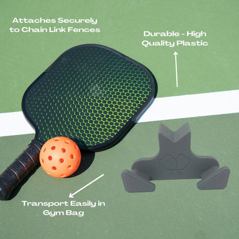 A Chatelet Manufacturing Pickleball Paddle Chain Link Fence Holder rests on the court, showcasing its USA-made quality—securely mounts your paddle to chain link fences, is compact for easy transport, and is an essential accessory for every player’s gym bag.