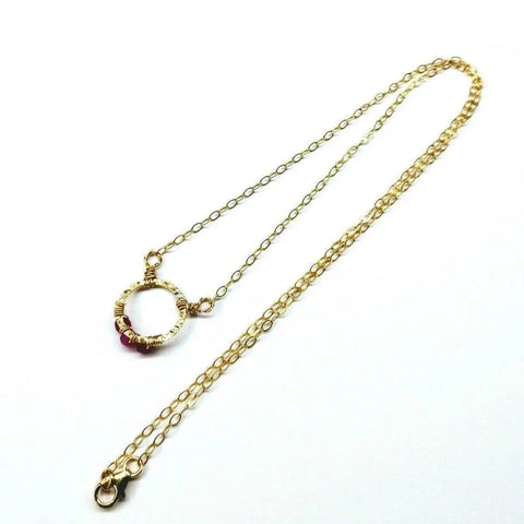 The Alexa Martha Designs Gold Filled Pink Chalcedony Open Circle Necklace features a delicate gold chain with a circle pendant, accented by pink and gold beads, shown on a white background.