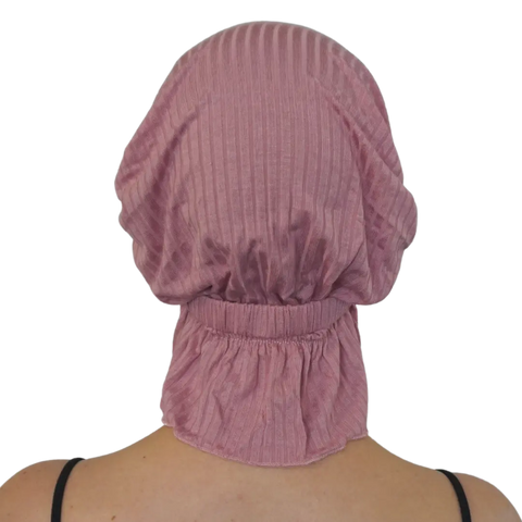 A person seen from behind wears the TAYLOR CHEMOBEANIE® by Chemo Beanies®—a pink ribbed slip-on beanie with gathered elastic at the base and neck, designed for hair loss headwear and extending down the back of the neck.
