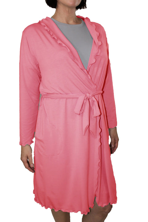 Wearing a knee-length pink Lettuce-Edge Robe by Goodnighties, featuring ruffled edges, a tie belt, and long sleeves over a light gray top. Only the lower part of the person’s face is visible; their head is partially out of frame.