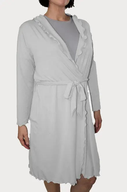 A person in a light gray, knee-length Goodnighties Lettuce-Edge Robe with ruffled edges, tie belt, and two pockets stands against a plain white background.