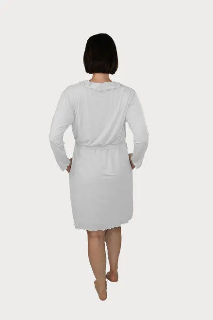 A woman with short dark hair stands barefoot, hands on hips, shown from the back wearing the Goodnighties Lettuce-Edge Robe, made in America, against a plain white background.