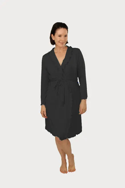 A woman with short dark hair smiles while barefoot, wearing the Goodnighties Lettuce-Edge Robe—an American-made, knee-length robe with long sleeves, a tie waist, and scalloped lettuce-edge details—against a plain white background.