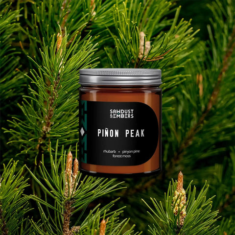 The Piñon Peak - Signature Candle by Sawdust & Embers, crafted in brown glass, offers a mountain home scent with notes of rhubarb, piñon pine, and forest moss.