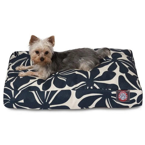 A small Yorkshire Terrier rests on the Majestic Pet Plantation Rectangle Dog Bed, which has a washable cover with large navy blue leaves on white and a red and white logo in the corner.