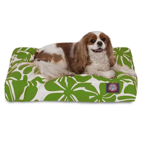 A brown and white dog lies happily on the Majestic Pet Plantation Rectangle Dog Bed with a green and white leafy pattern, featuring a washable cover and premium polyester fill for comfort.