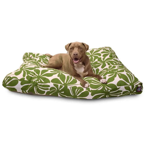 A brown dog with white markings relaxes on the Majestic Pet Plantation Rectangle Dog Bed, featuring a large green and white leaf pattern, looking forward with its mouth open.