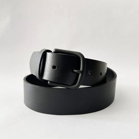 The Baxter Leather Belt - 1.5 Wide by Rogue Industries, made from premium black cowhide leather with a matte black buckle, is coiled in a loose circle on a plain white background.