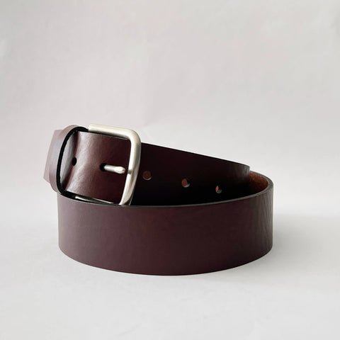 The Baxter Leather Belt by Rogue Industries, 1.5 wide and made from premium dark brown cowhide leather with a silver rectangular buckle, is shown coiled on a plain white background.
