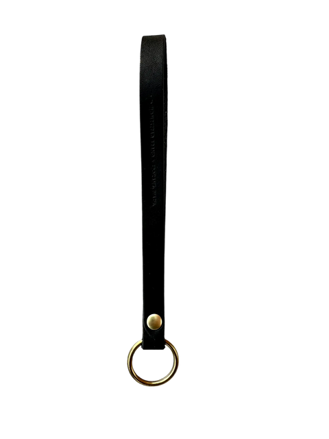 The Homestead Brand Standard Wristlet No. 1604 is a black full grain leather strap keychain with a gold metal ring and stud, shown vertically on a black background. Handmade in the USA for lasting quality.
