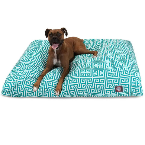 A brown and white dog lies on the Majestic Pet Towers Rectangle Dog Bed, featuring a large turquoise and white geometric pattern with a removable cover, looking at the camera with its mouth open and tongue out.