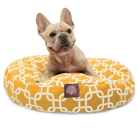 A light brown French Bulldog sits on the Majestic Pet Links Round Dog Bed, which has a white geometric pattern, a washable removable cover, and a paw print label on the front.