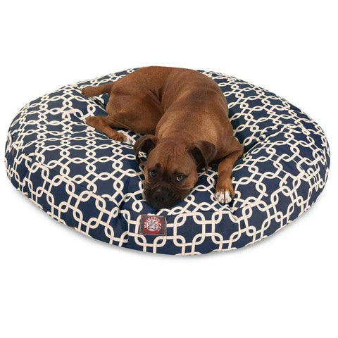 A brown dog lies on the Majestic Pet Links Round Dog Bed, featuring a navy blue color with a white geometric pattern, and rests its head on the machine washable bed.