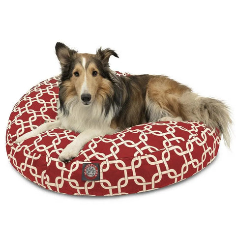 A long-haired dog with brown, black, and white fur relaxes on the Majestic Pet Links Round Dog Bed, featuring a white interlocking pattern. Its removable cover is machine washable for easy care.