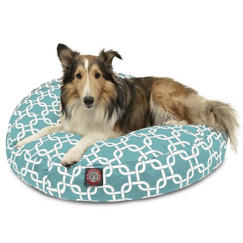 A long-haired dog with brown, black, and white fur is lying on the Majestic Pet Links Round Dog Bed, which features a white geometric pattern and a removable cover for easy washing.