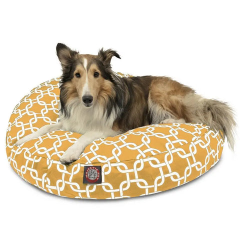 A fluffy brown and white dog with upright ears relaxes on the Majestic Pet Links Round Dog Bed, which is washable and features a white interlocking pattern.