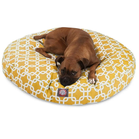A brown dog is resting on the Majestic Pet Links Round Dog Bed, which features a round shape and a white geometric pattern on a yellow, washable, removable cover.