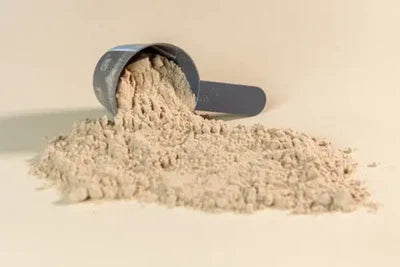 Beige powder spilling out of a scoop on a beige background