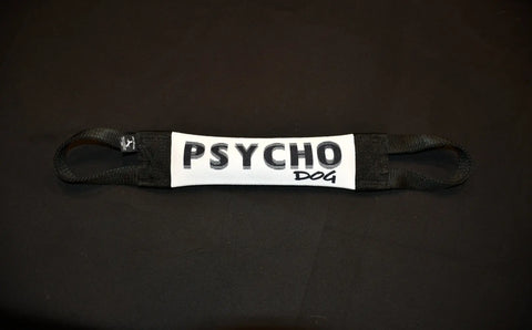 The Psycho Dog Fire Hose Training Tug by Bulletproof Pet Products Inc is a white and black heavy-duty dog toy with handles at both ends and PSYCHO DOG printed in the middle, shown on a black background.