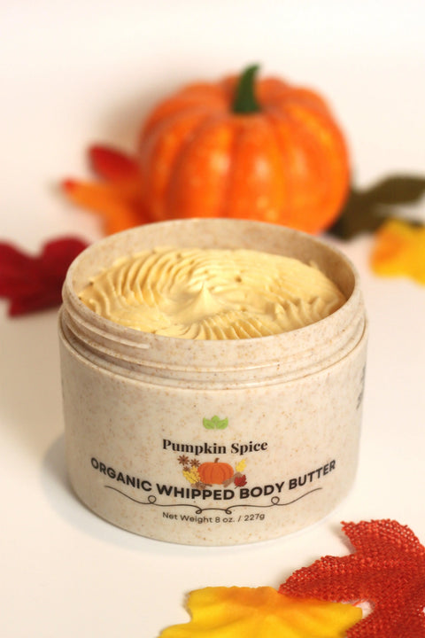 An open jar of Forev'Herbs Pumpkin Spice Organic Whipped Body Butter displays its creamy, swirled texture. Surrounded by autumn decor, this luxurious butter promises deep hydration with every use.