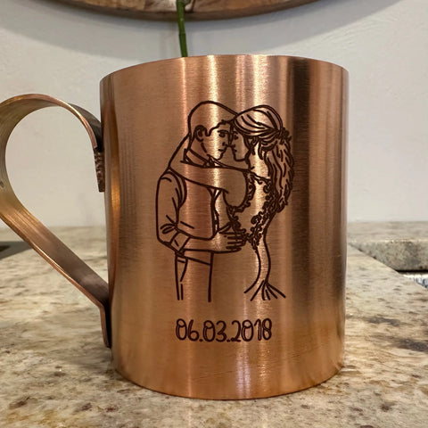 A Havens Luxury Metals Pure Copper Mule Mug, handcrafted in the USA and engraved with a couple embracing above the date 06.03.2018, rests on a speckled countertop.