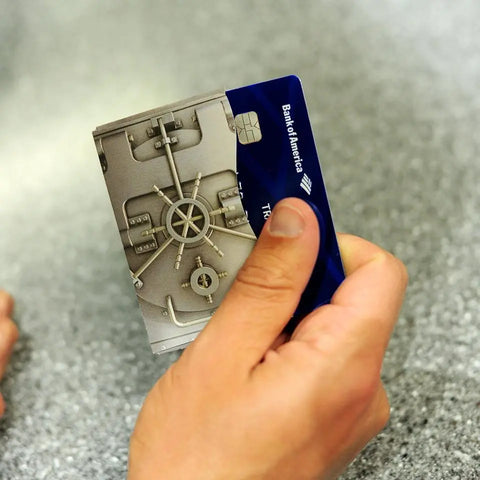 A person holds two credit cards, one with a vault door design and another with a blue Bank of America logo, against a speckled gray background—perfect for pairing with Rogue Industries Platinum Vault RFID Blocking Credit Card Sleeves for added security.