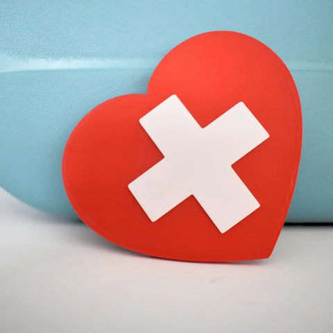 The Boglets RN Nurse Charm by Chatelet Manufacturing features a red heart with a white X, ideal as a unique nurse gift or for personalizing tote bags like Bogg Bags or Simply Southern totes.