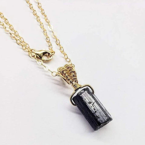 The Raw Black Tourmaline Gemstone Necklace by Alexa Martha Designs features a gold filled wire wrapped rough black tourmaline pendant on a doubled chain with lobster clasp, creating a striking handmade Montana jewelry piece.